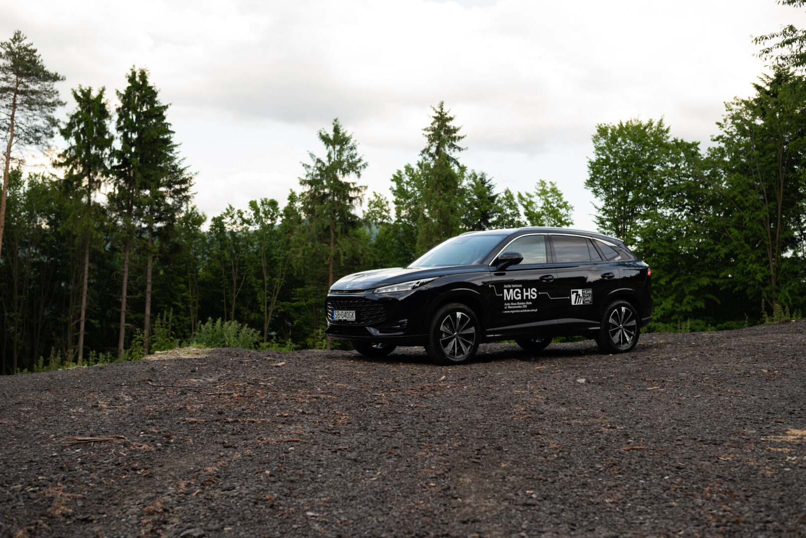 Samochód MG HS stoi zaparkowany na tle lasu