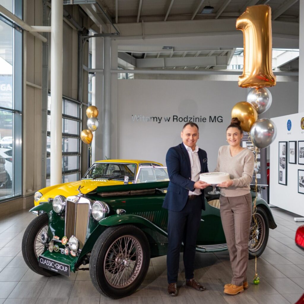 Pracownicy MG Auto-Boss trzymający tort w salonie, z okazji pierwszych urodzin