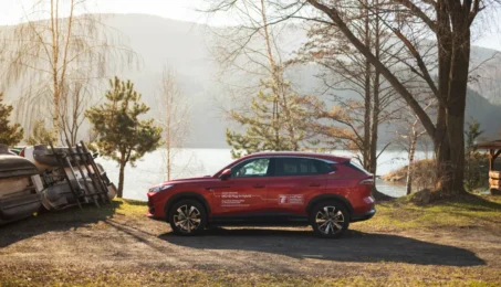 Czerwony MG HS Plug-in Hybrid zaparkowany nad jeziorem